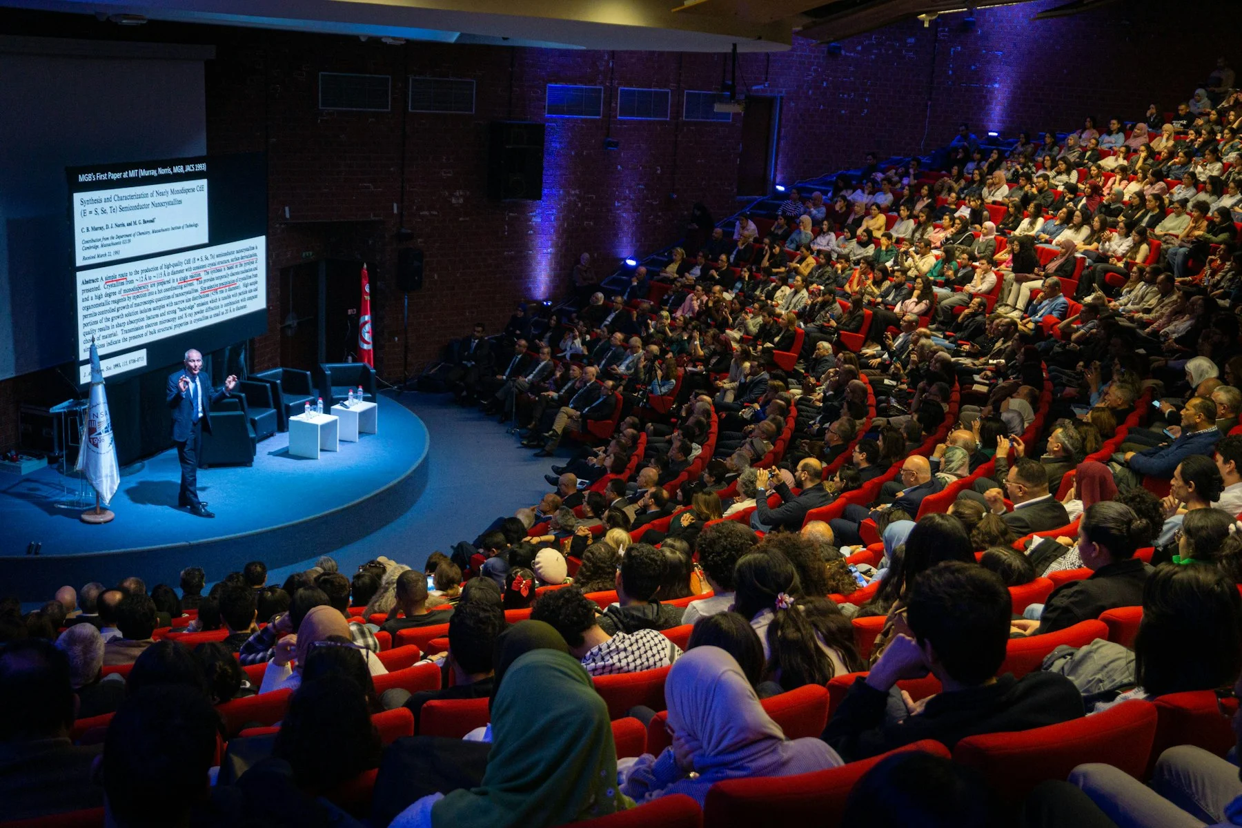 Speaker presenting to a large audience at a conference